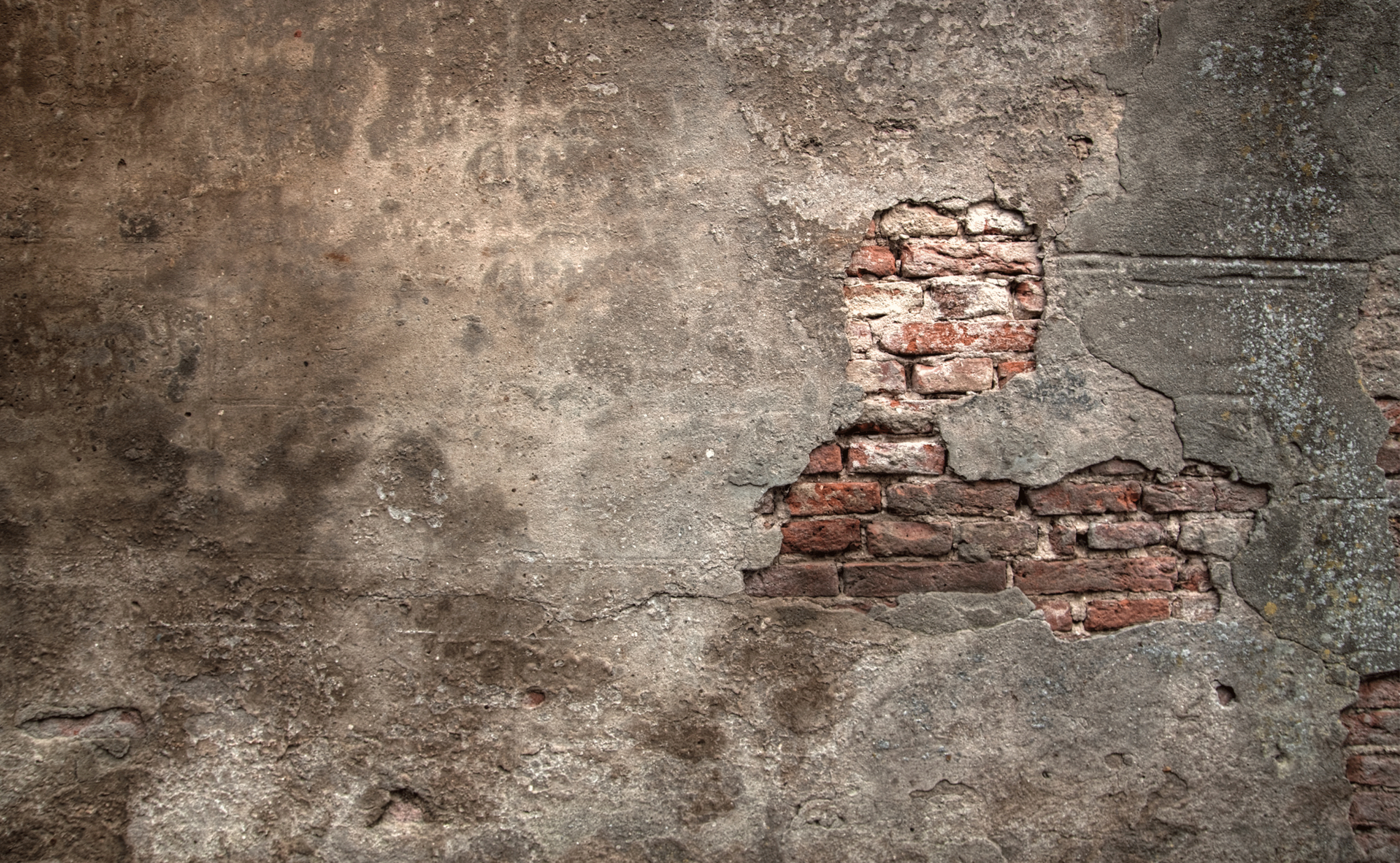 An old plastered wall with the plaster cracking exposing old bricks
